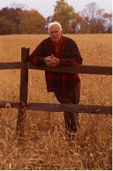 Agriculteur âgé appuyé sur la clôture d'un champ de céréales